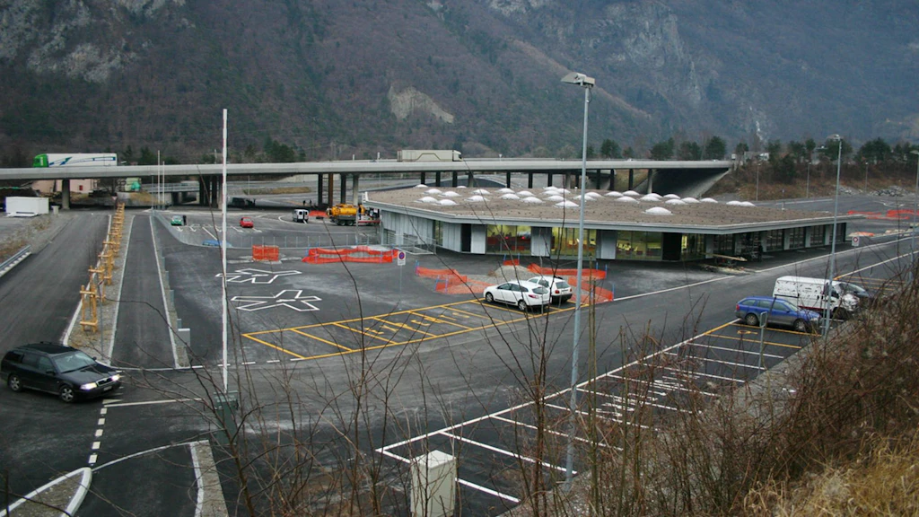 Bâtiment de plain-pied situé sur une grande esplanade en béton, avec de nombreuses places de stationnement pour camions et voitures.