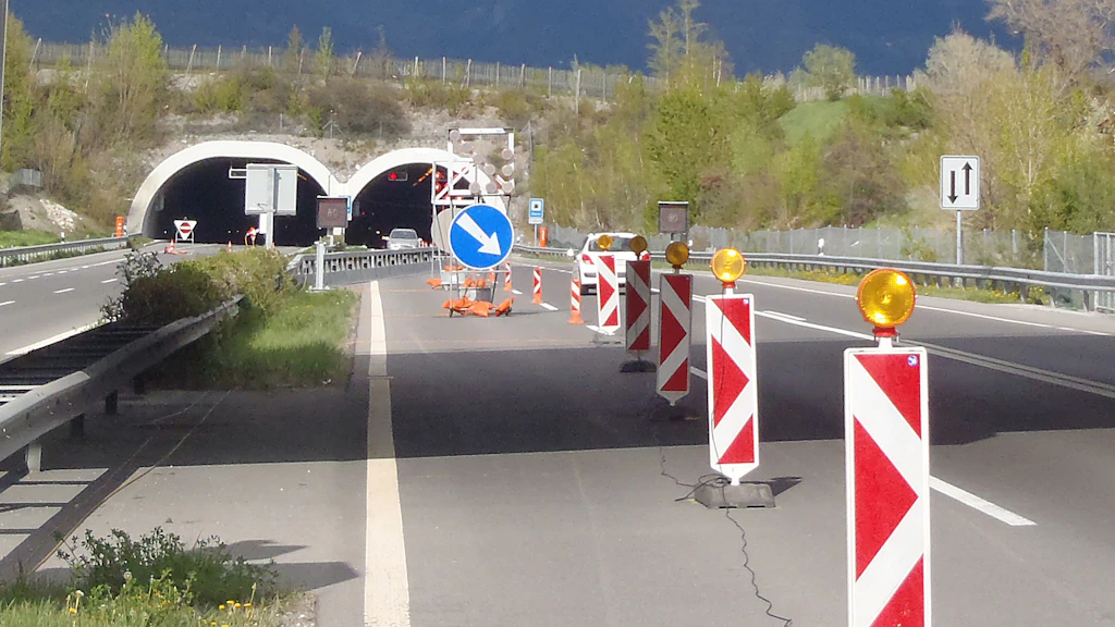 Straßensperrung mit Leitbaken und Warnleuchten für ein Gegenvekehrsregime vor dem zweiröhrigem Tunnel Sierre