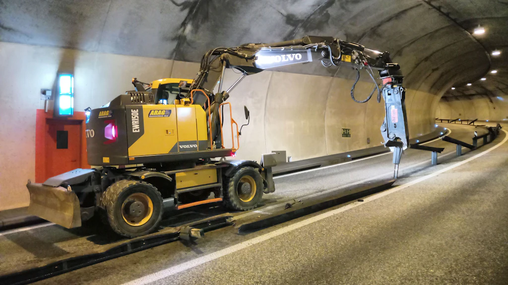 Bauarbeitsfahrzeug mit Hydraulikhammer in einem Tunnel neben einer Mitteltrennung