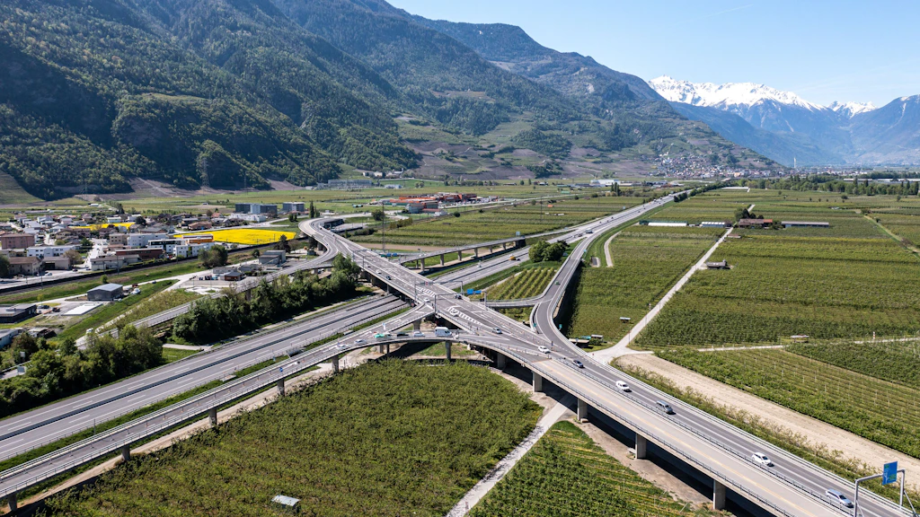 Viaduc autoroutier traversant une vallée agricole avec montagnes en arrière-plan