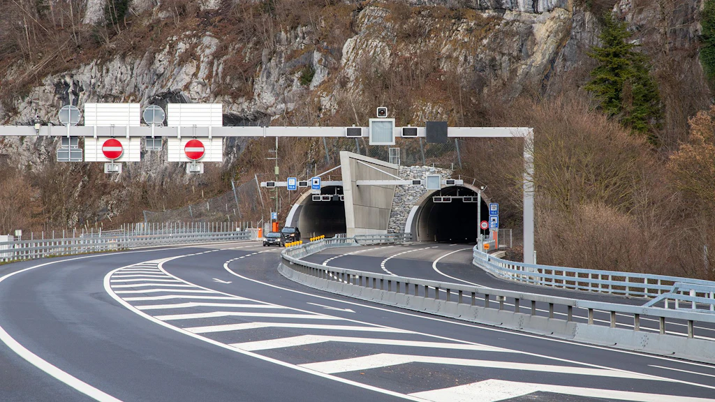 Autobahn mit zwei Tunnelröhren, getrennt durch eine Antirezirkulationswand, umgeben von felsigem Gelände und Verkehrszeichen mit Einfahrtsverbot