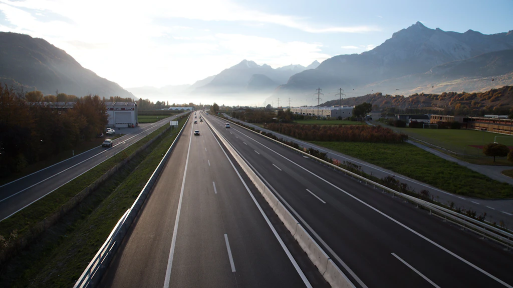 Autobahn mit wenig Verkehr zwischen Bergen unter bewölktem Himmel
