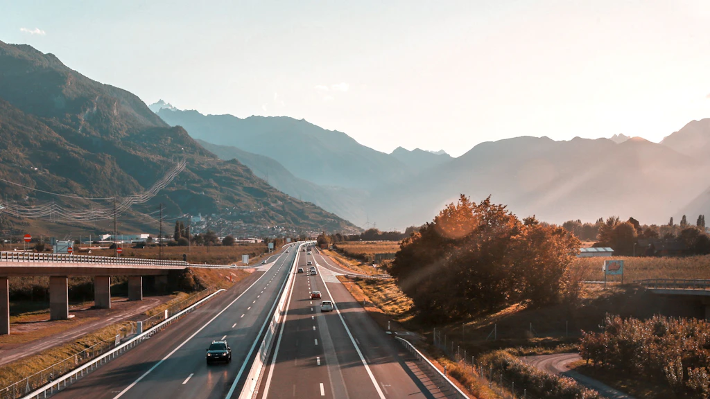 Autoroute avec plusieurs véhicules entre des montagnes sous un ciel clair