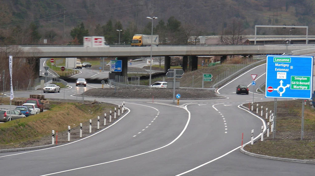 Giratoire à plusieurs voies avec panneaux de signalisation près d'une entrée d'autoroute en zone rurale