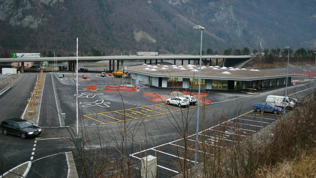 Bâtiment de plain-pied situé sur une grande esplanade en béton, avec de nombreuses places de stationnement pour camions et voitures.