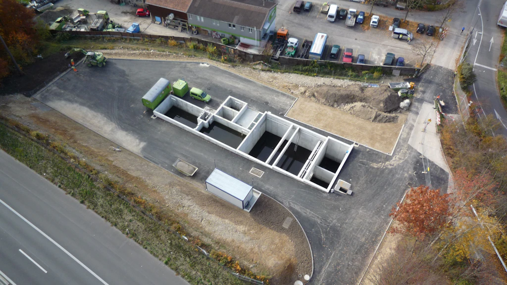 Luftaufnahme einer Baustelle mit mehreren rechteckigen Betonfundamenten und angrenzenden Strassenabschnitten